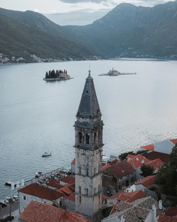 a clock tower on top of a building next to a body of water, by Emma Andijewska, pexels contest winner, renaissance, “ aerial view of a mountain, boka, attacked submarine in background, two medium sized islands