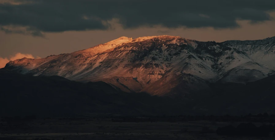 a mountain covered in snow under a cloudy sky, inspired by Elsa Bleda, unsplash contest winner, australian tonalism, epic red - orange sunlight, slightly tanned, (night), mount doom