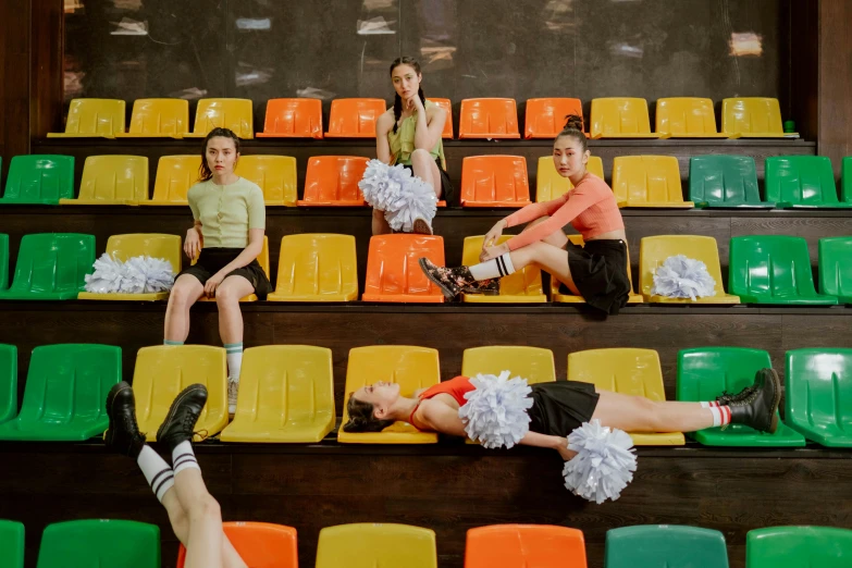 a group of people sitting on top of a green and yellow bleachers, pexels contest winner, antipodeans, a teenage girl cheerleader, indoor scene, lying on an empty, kiko mizuhara