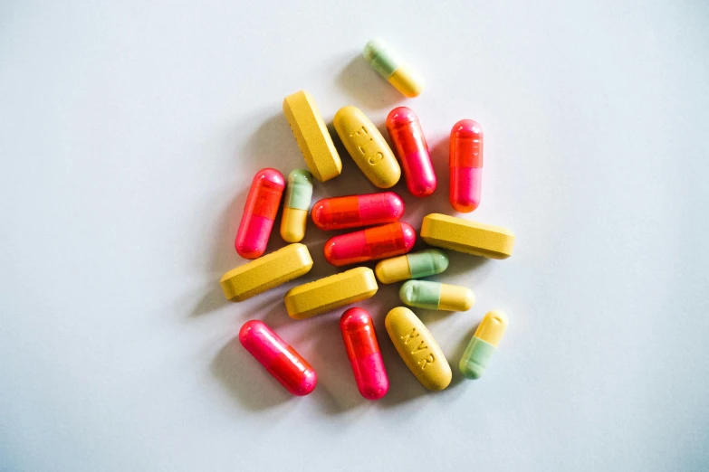 a pile of colorful pills on a white surface, by Jessie Algie, antipodeans, pink and yellow, tubes, shot with sony alpha, yellow red scheme