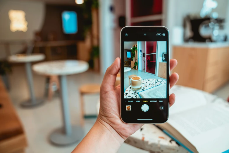 a person taking a picture of a coffee cup, photograph of 3d ios room, looking towards camera, ecommerce photograph, a wooden