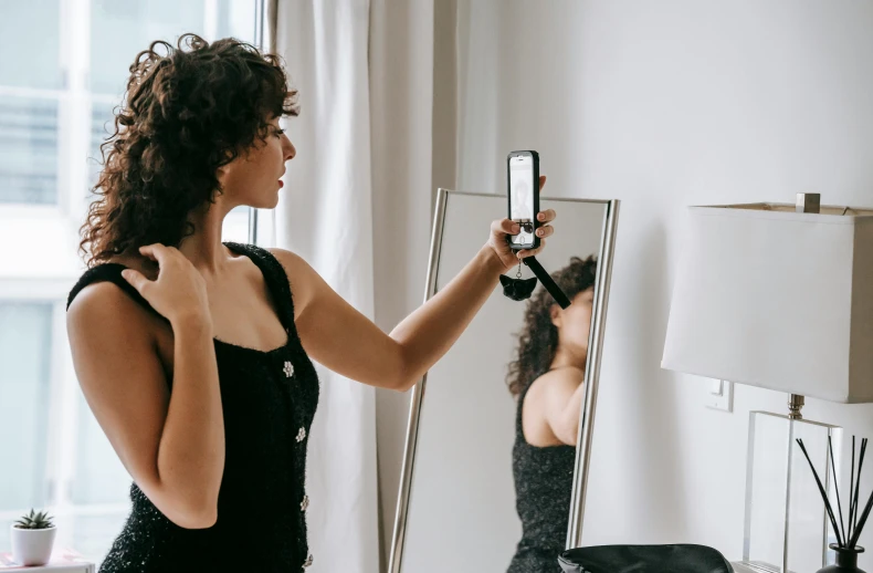 a woman taking a picture of herself in a mirror, trending on pexels, art nouveau, brown curly hair, wearing a black bodysuit, profile image, pixel perfect