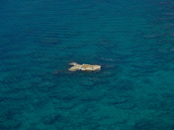 a rock in the middle of a body of water, by Francesco Furini, pexels, minimalism, from 1 0 0 0 feet in distance, cyprus, whale carcass, screensaver