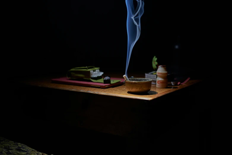 a lit incense stick sitting on top of a wooden table, a still life, by Eglon van der Neer, trending on unsplash, mingei, smoke coming out of her mouth, over a dish and over a table, set at night, praying with tobacco