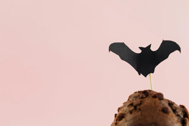a chocolate ice cream with a black bat on top, trending on pexels, conceptual art, cupcake, paper cutout, hero, up there