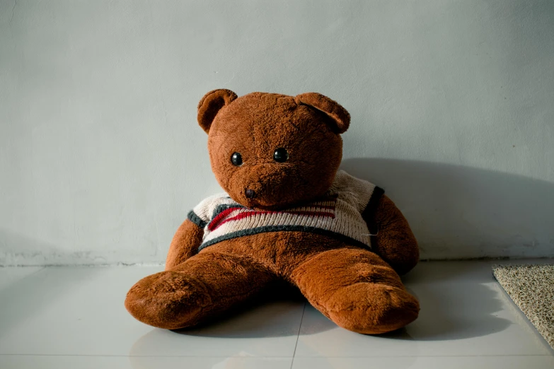a brown teddy bear sitting on the floor
