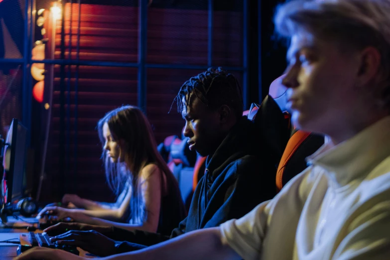 a group of people sitting in front of computers, by Nick Fudge, pexels, realism, sierra entertainment games, background image, blue and orange lighting, high school