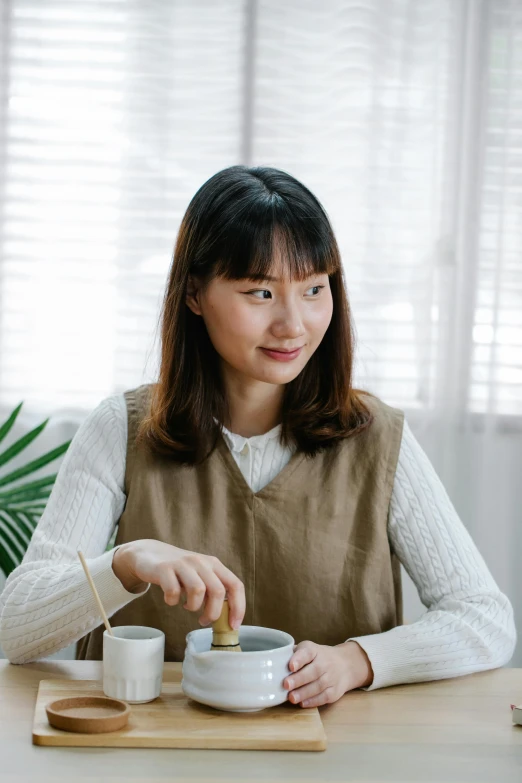 a woman sitting at a table with a cup of tea, inspired by Kim Jeong-hui, wearing a linen shirt, pokimane, gongbi, warm friendly expression