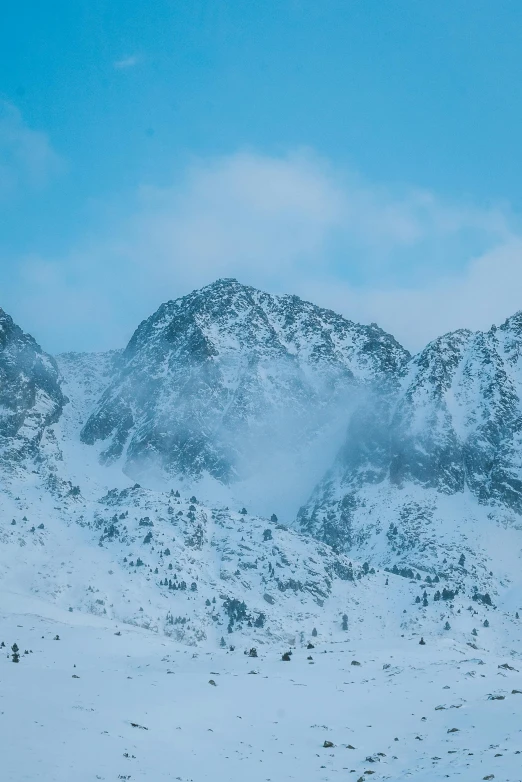 a group of people riding skis down a snow covered slope, large rocky mountain, covered in snow, pyranees, unsplash 4k