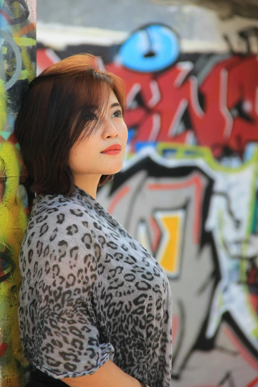 a woman leaning against a graffiti covered wall, a picture, by Ric Estrada, bokeh in the background only, multicolored, portrait of modern darna, trending photo