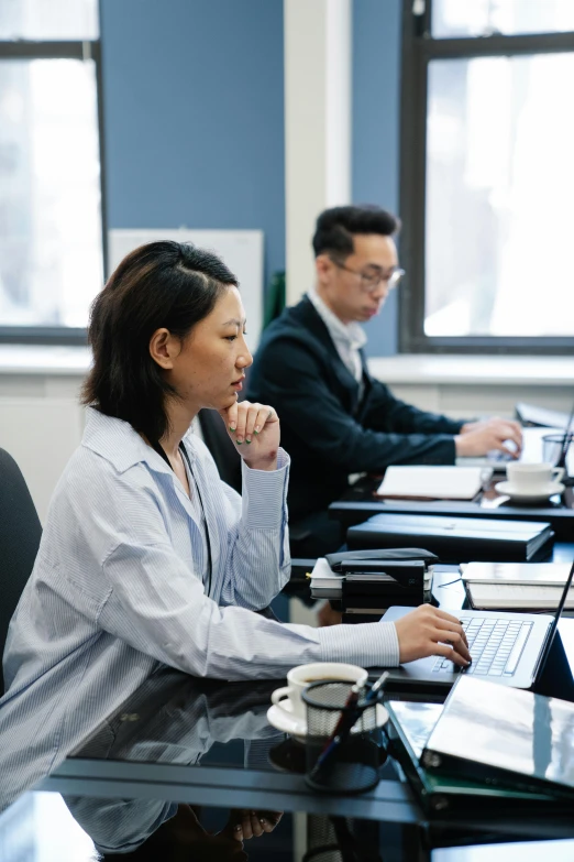 a group of people sitting at a table with laptops, inspired by Fei Danxu, trending on unsplash, medium shot of two characters, offices, royal commission, asian human