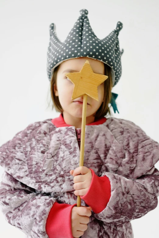 a little girl wearing a crown and holding a wand, an album cover, inspired by Elsa Beskow, unsplash, giant wooden club, wearing star filled mage robes, studio photo, embarrassing