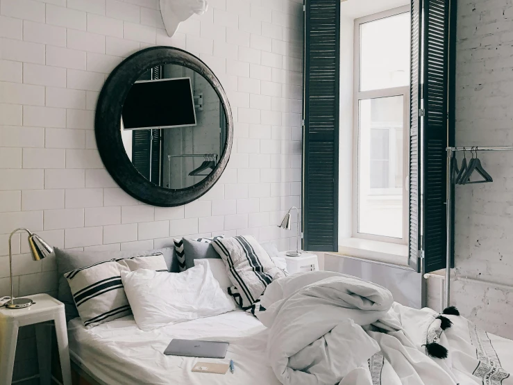 a white bed sitting in a bedroom next to a window, by Carey Morris, trending on unsplash, bauhaus, huge black circle, shutters, with many mirrors, glossy white