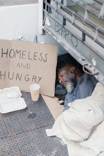 a homeless man with a sign that says homeless and hungry, a photo, trending on unsplash, renaissance, instagram story, asleep, getty images, mukbang