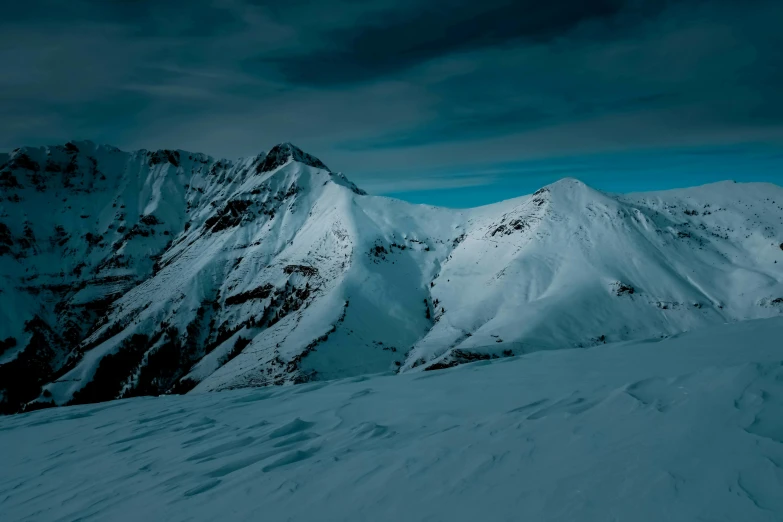 a person standing on top of a snow covered mountain, a matte painting, pexels contest winner, minimalism, dark winter evening, dominant wihte and blue colours, panoramic photography, alpes