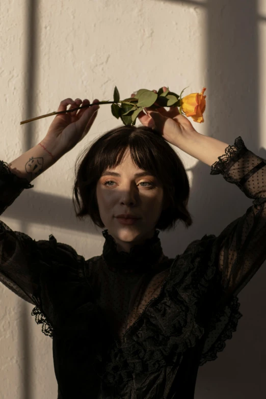 a woman holding a rose up to her head, inspired by Elsa Bleda, french bob, marigold, press shot, twigs