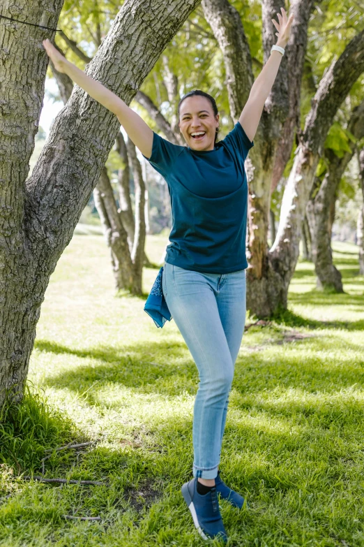 a woman jumping in the air in a park, inspired by david rubín, happening, wearing jeans, on a tree, pose(arms up + happy), chilean