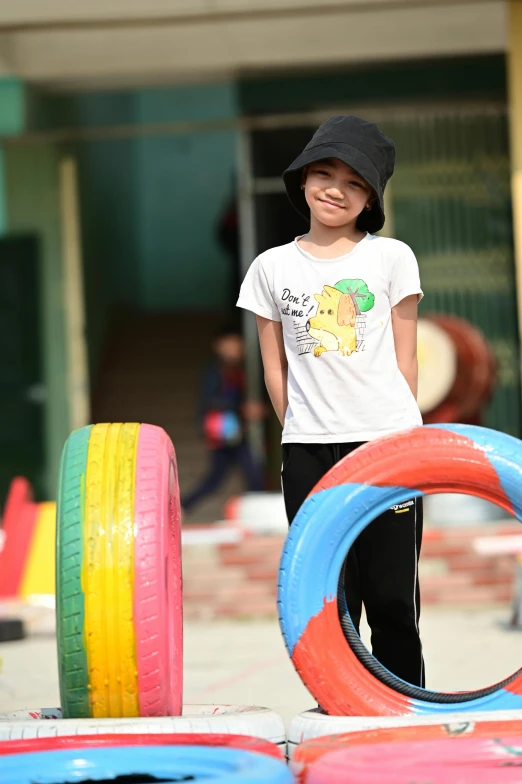 a young boy standing next to a pile of tires, by Zahari Zograf, pexels contest winner, young asian girl, softplay, ( ( ( colorful ) ) ), vietnam soldier with skateboard
