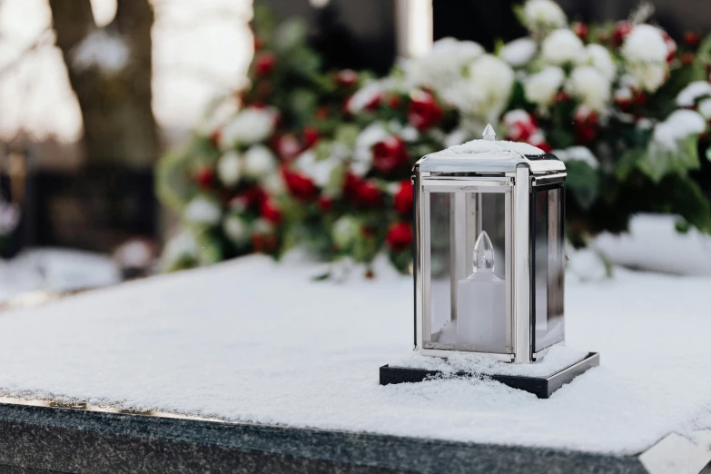 a candle sitting on top of a table covered in snow, in a graveyard, silver white red details, argand lamp, subtle detailing