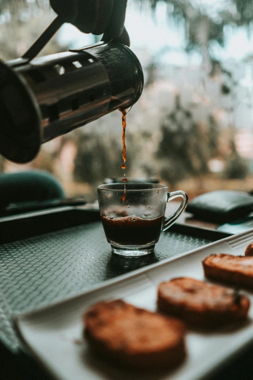 a person pouring coffee into a cup next to some cookies, by Niko Henrichon, pexels contest winner, glossy surface, thumbnail, multiple stories, beautiful surroundings