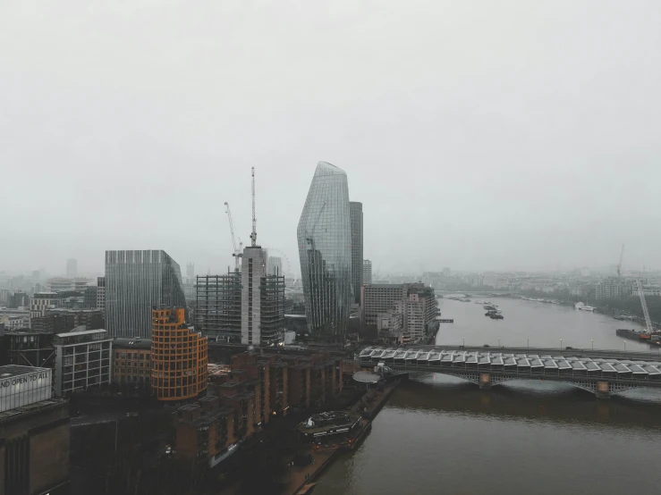 a river running through a city next to tall buildings, inspired by Thomas Struth, pexels contest winner, foggy rainy day, london architecture, grey, view from high