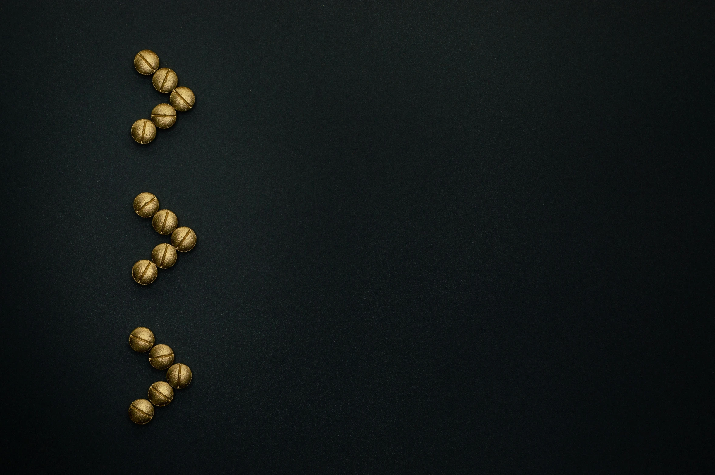 gold balls on a black background, an album cover, inspired by Lucio Fontana, trending on pexels, background image, pills, a high angle shot, clover