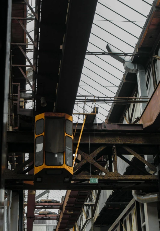 a yellow train traveling through a train station, a picture, unsplash, sitting in a crane, ((rust)), in sao paulo, low quality photo
