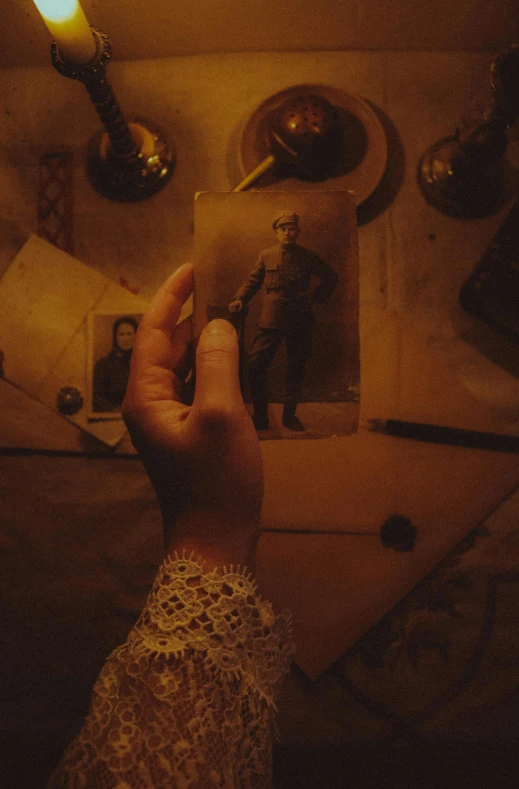 a person holding a candle on top of a table, from the grand budapest hotel, grainy damaged photo, steampunk aesthetic, wwi