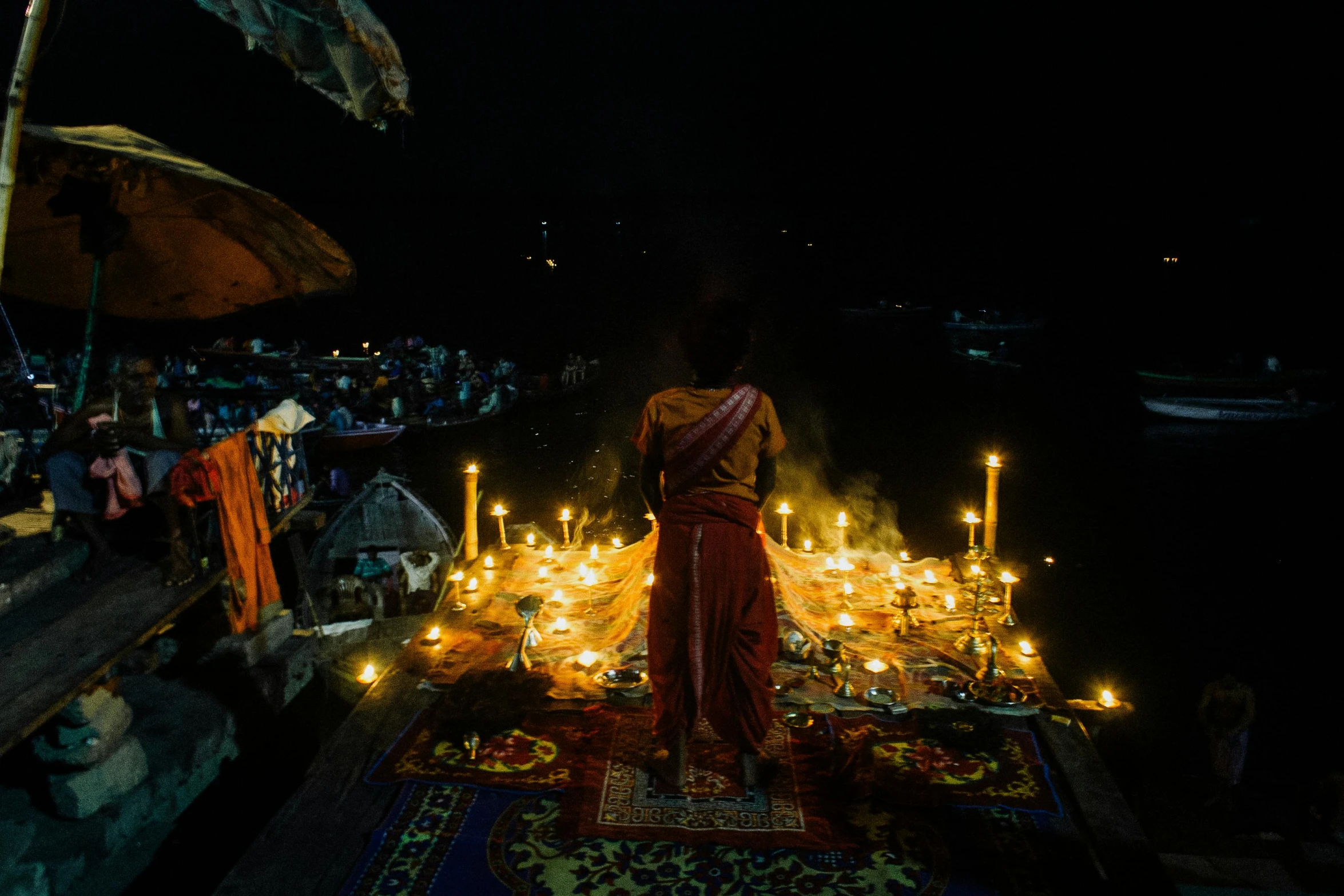 a woman standing next to a bunch of lit candles, pexels contest winner, submerged temple ritual scene, photo taken from a boat, she is dressed in shaman clothes, view from above