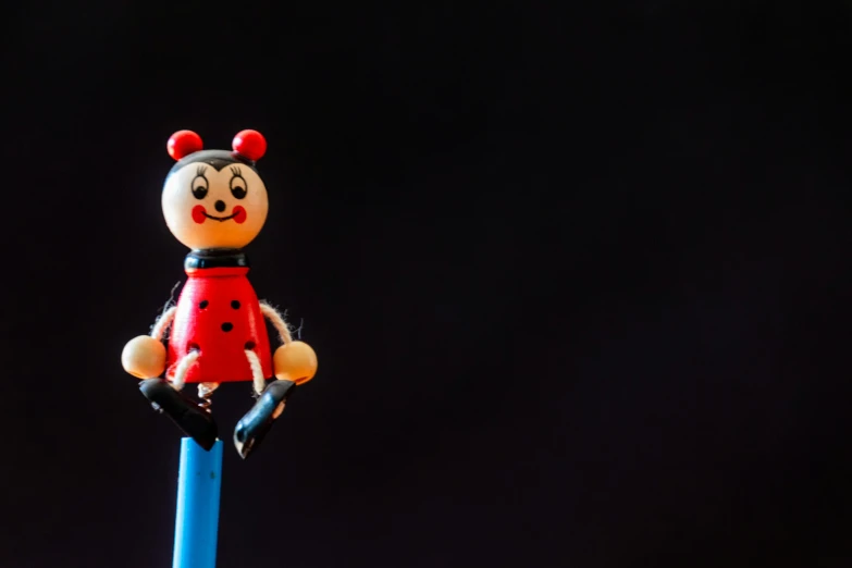 a toy lady bug sitting on top of a blue pencil, unsplash, figuration libre, standing with a black background, portrait of mickey mouse, on stilts, frightening surroundings