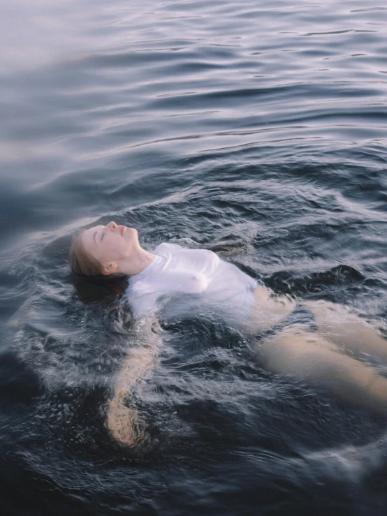 a man floating on top of a body of water, photo of young woman, subsurface scandering, recovering from pain, in its dying breath