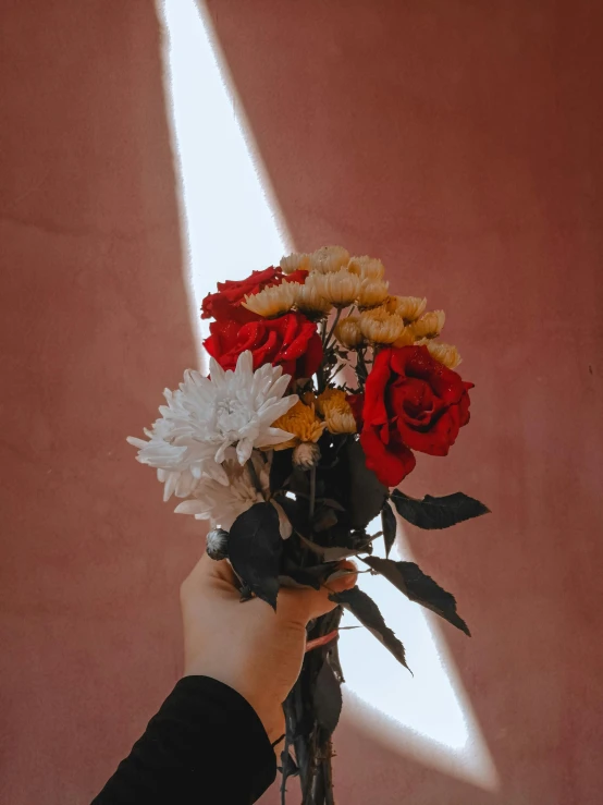 a person holding a bunch of flowers in their hand, by Robbie Trevino, red black white golden colors, trending photo