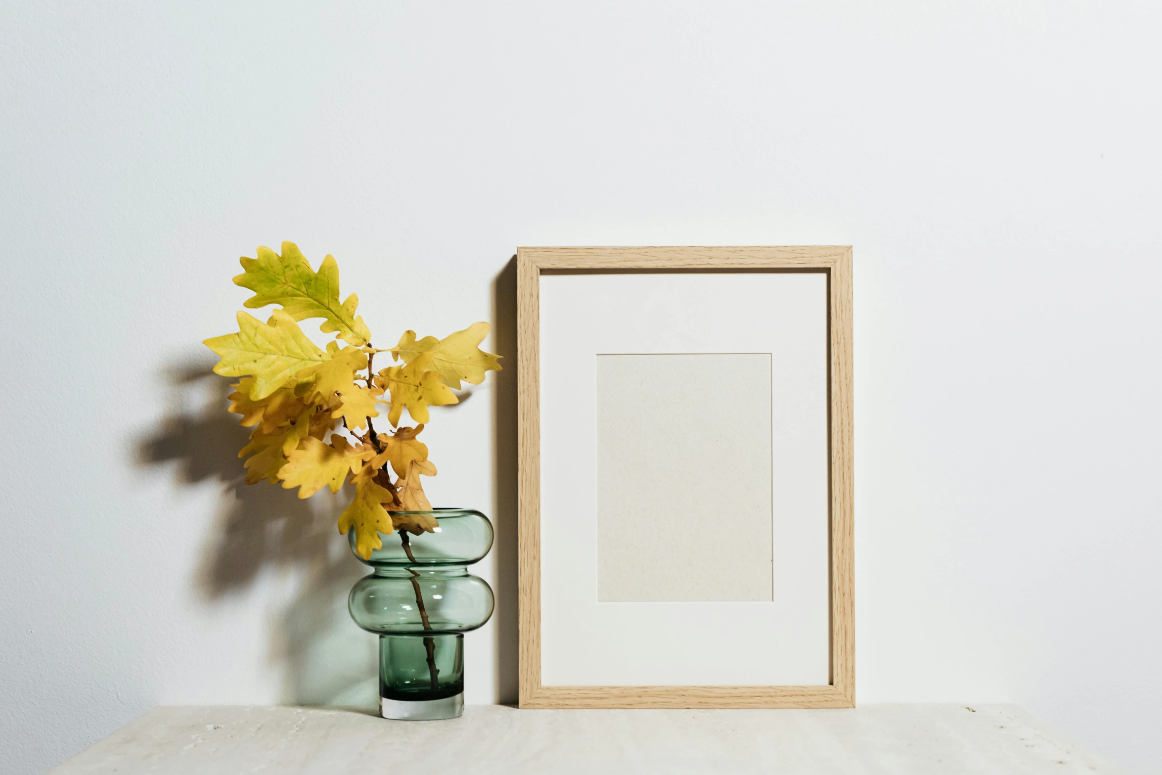 a picture frame sitting on top of a table next to a vase, pexels contest winner, visual art, autumnal, oak, clear glass wall, set against a white background