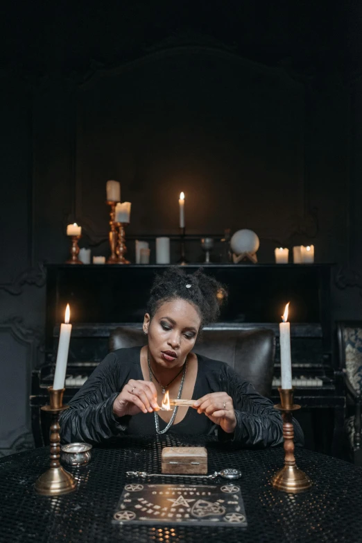 a woman sitting at a table with a cake in front of her, inspired by Carrie Mae Weems, trending on pexels, renaissance, casting a flame spell, holding nevermore, lit candles, studio photo
