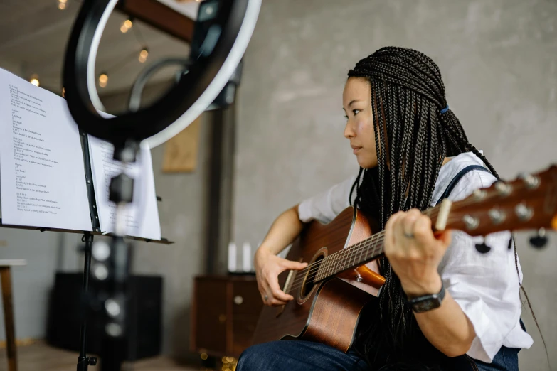 a woman with dreadlocks playing a guitar, pexels contest winner, hurufiyya, avatar image, half asian, with a ponytail, well lit professional photo