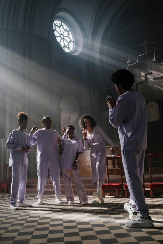 a group of people standing on top of a checkered floor, an album cover, inspired by David LaChapelle, trending on pexels, antipodeans, scene set in a church, white uniform, prison scene, perfectly lit. movie still