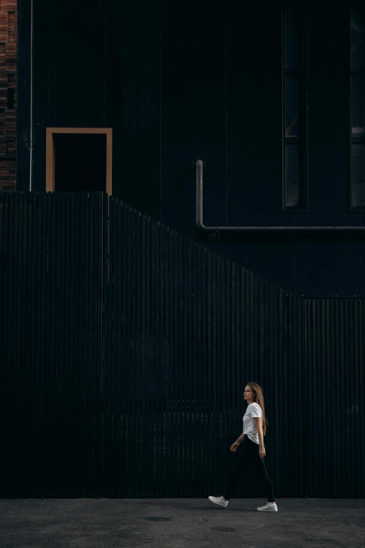 a woman walking down a sidewalk in front of a building, a picture, unsplash contest winner, minimalism, on a black wall, 15081959 21121991 01012000 4k, panoramic view of girl, alexey gurylev