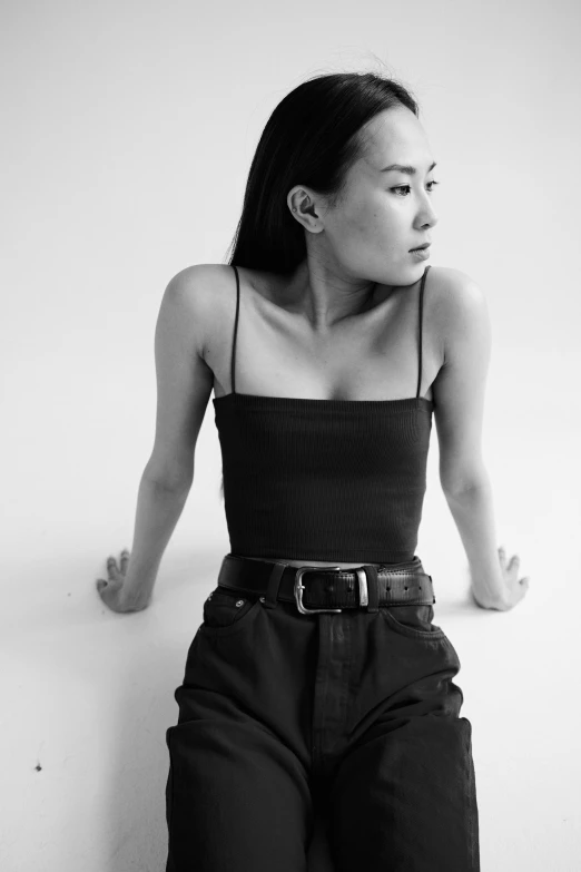 a black and white photo of a woman sitting on the floor, inspired by Wang E, tumblr, wearing a cropped top, her hand is on her waist, steve zheng, album cover