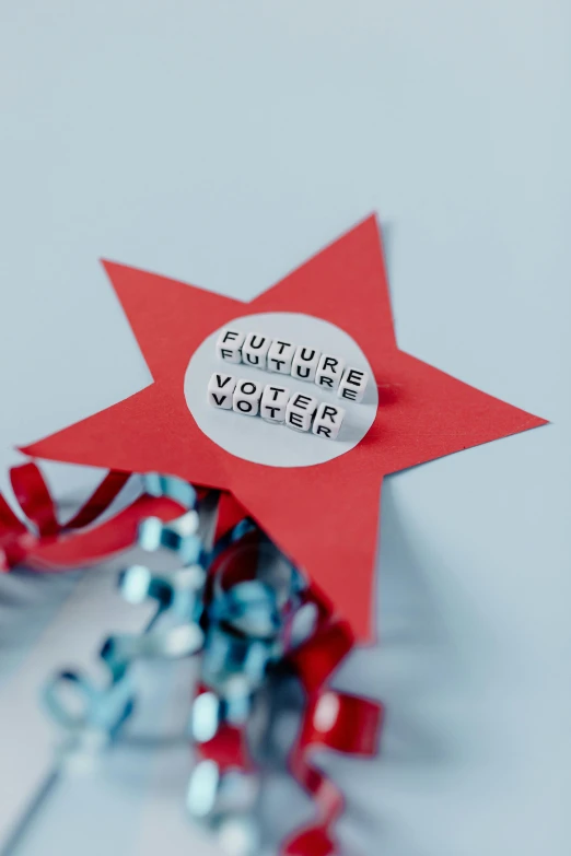 a red star sitting on top of a pile of confetti, by Violet Fuller, futurism, pair of keycards on table, state of the union, promo material, close - up photograph