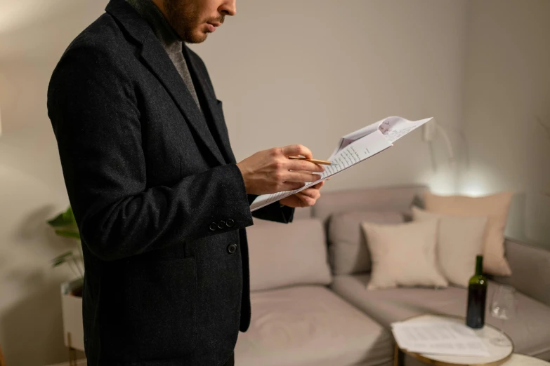 a man standing in a living room holding a piece of paper, by Joseph Severn, pexels contest winner, couch desk, lit from the side, detailed information, mid - action