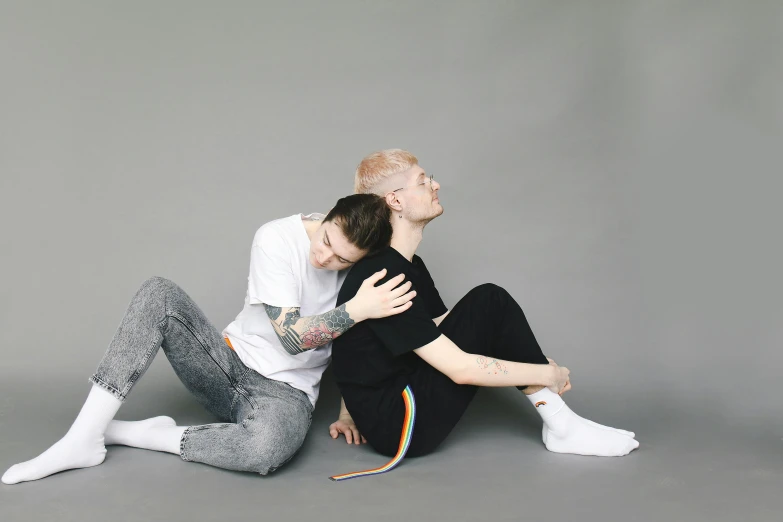 a man and a woman sitting next to each other, by Emma Andijewska, lgbtq, hugging his knees, shaved sides, laying on their back