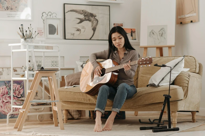 a woman sitting on a couch playing a guitar, pexels contest winner, asian female, leaving a room, youtube thumbnail, multiple stories