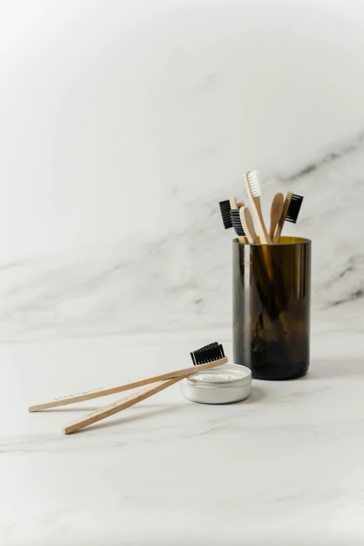 a glass filled with toothbrushes sitting on top of a counter, by Nicolette Macnamara, minimalism, ivory and black marble, made of bamboo, amber, professional product photo