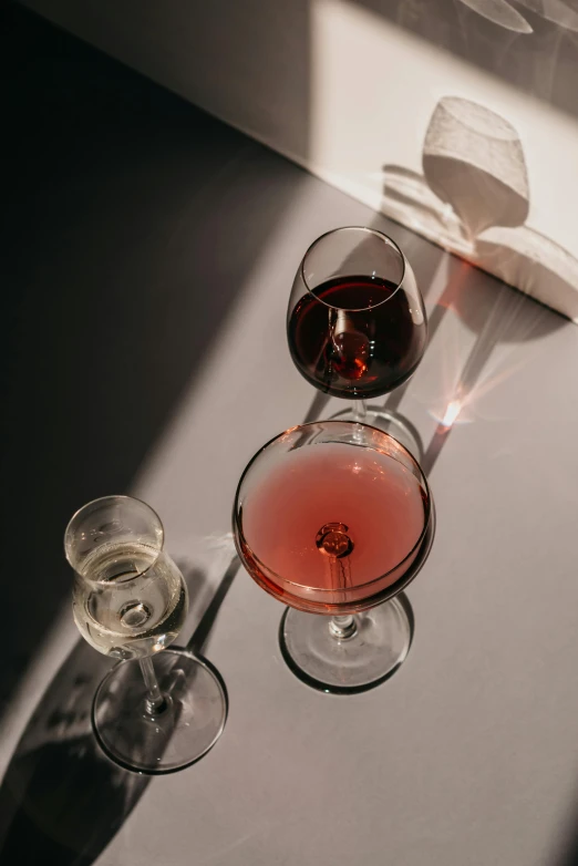 a couple of wine glasses sitting on top of a table, a still life, pexels contest winner, drop shadows, detailed product image, multiple stories, drinking cocktail