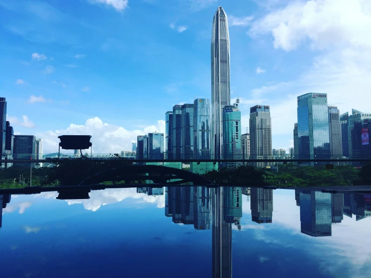 a large body of water surrounded by tall buildings, an album cover, pexels contest winner, shenzhen, blue sky, glass and steel, avatar image