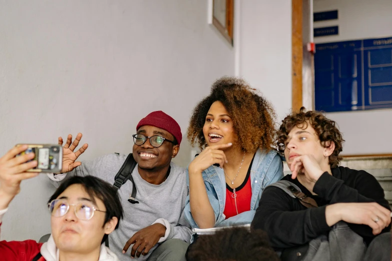 a group of people sitting on top of a couch, trending on pexels, in a school classroom, looking her shoulder, ethnic group, promotional image