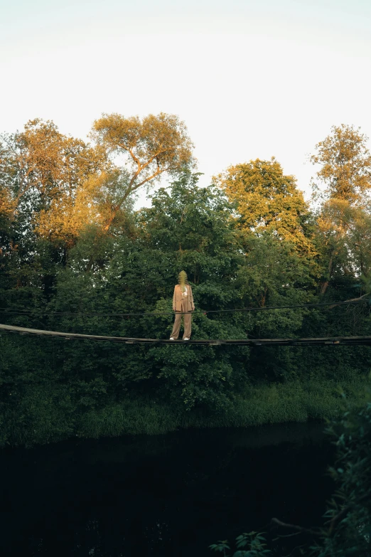 a person standing on a rope over a body of water, in the countryside, canopy, evening light, bridges