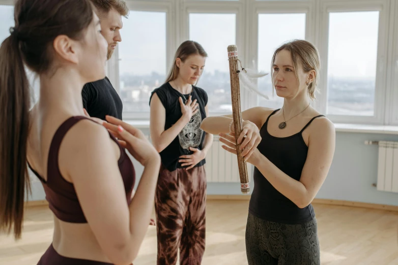 a group of women standing next to each other in a room, an album cover, by Emma Andijewska, pexels contest winner, danube school, holding a wooden staff, dance meditation, hasbulla magomedov, thumbnail