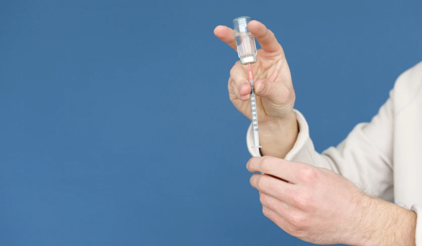 a close up of a person holding a toothbrush, holding a syringe, iv pole, with a blue background, sleek hands