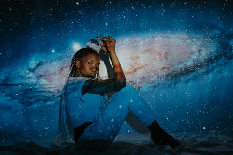 a woman sitting on top of a bed in front of a galaxy, an album cover, trending on pexels, afrofuturism, lunar themed attire, portrait photo, profile image, with glowing blue lights